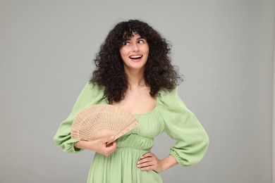Photo of Happy woman holding hand fan on light grey background
