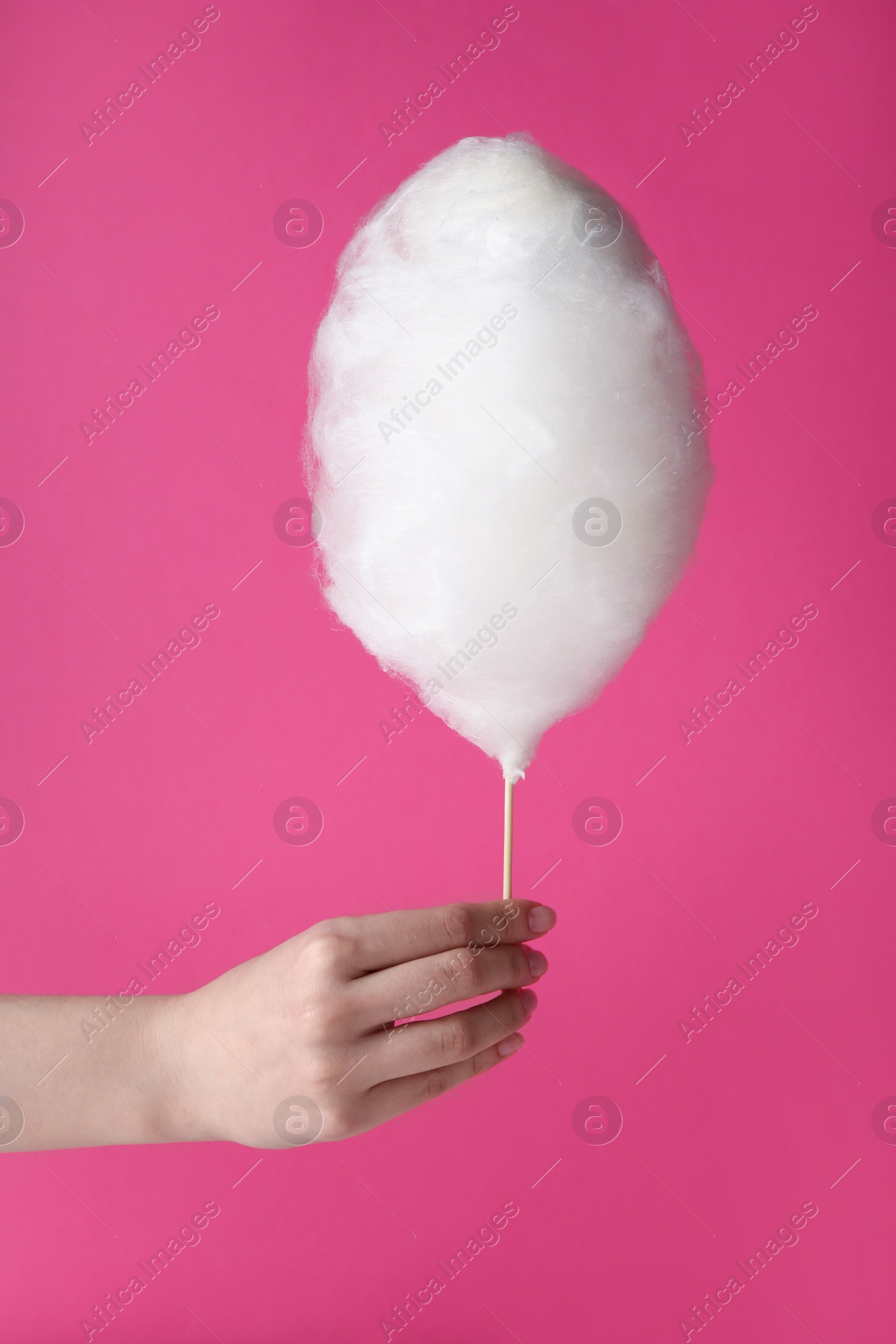 Photo of Woman holding sweet cotton candy on pink background, closeup