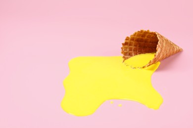 Photo of Melted ice cream and wafer cone on pink background, space for text