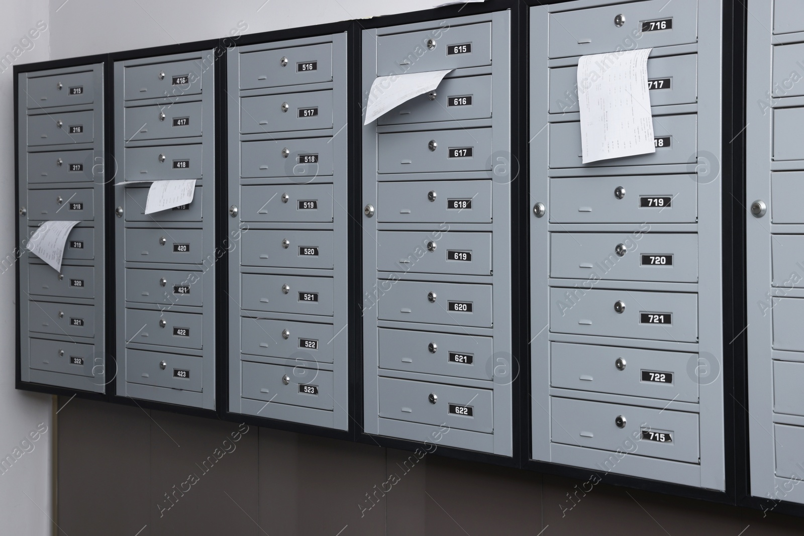 Photo of Closed grey metal mailboxes with receipts indoors