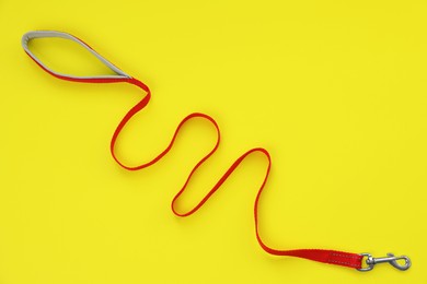 Red dog leash on yellow background, top view