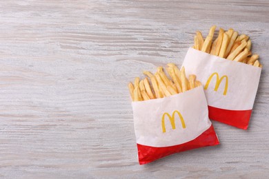 Photo of MYKOLAIV, UKRAINE - AUGUST 12, 2021: Two small portions of McDonald's French fries on white wooden table, flat lay. Space for text