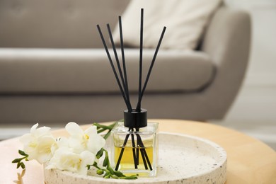 Photo of Reed diffuser with freesia on table in living room