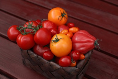 Photo of Basket with fresh tomatoes on wooden table