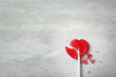 Broken heart shaped lollipop on gray background, top view with space for text. Relationship problems