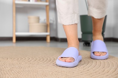 Photo of Woman wearing comfortable rubber slippers at home, closeup of legs