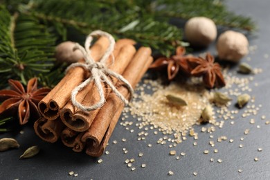 Photo of Cinnamon sticks and other spices on gray table, closeup