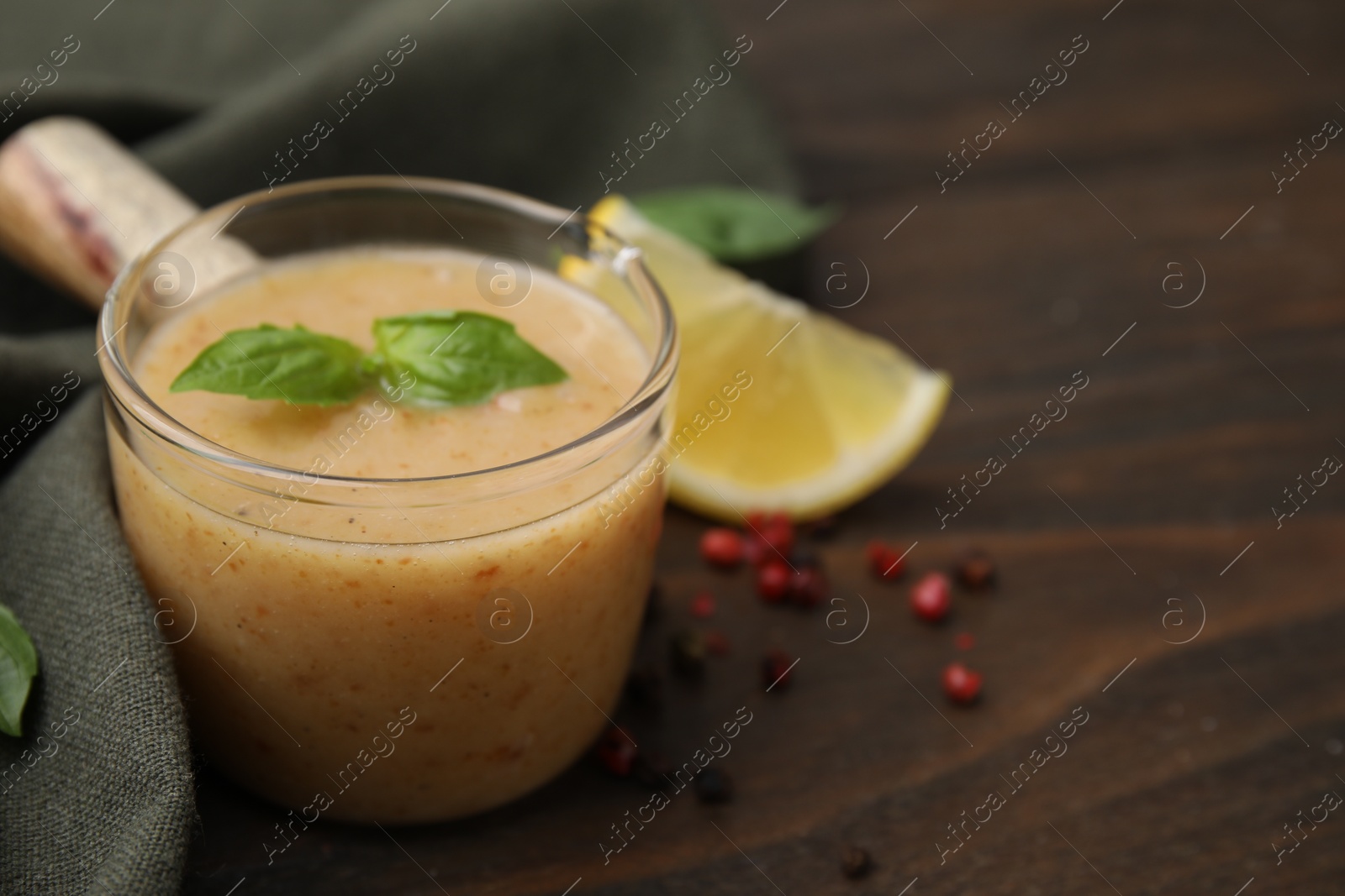 Photo of Delicious turkey gravy, basil, peppercorns and lemon on wooden table, closeup. Space for text