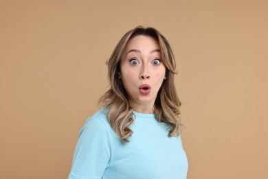 Portrait of surprised woman on beige background