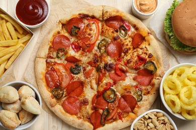 Pizza, onion rings and other fast food on wooden table, flat lay