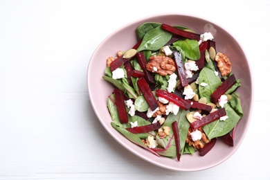 Photo of Delicious beet salad served \on white wooden table, top view. Space for text