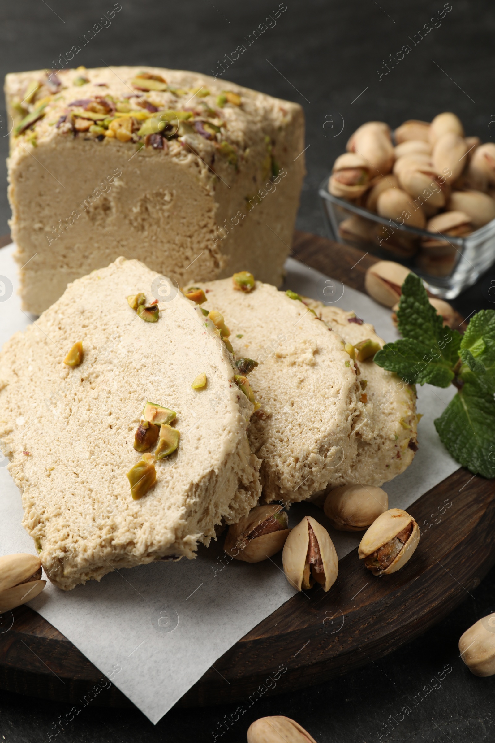 Photo of Tasty halva with pistachios and mint on table, closeup