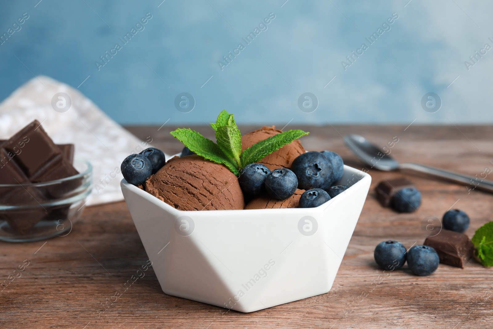 Photo of Bowl of chocolate ice cream and blueberries served on wooden table, space for text