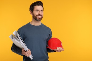Photo of Architect with hard hat and folders on orange background