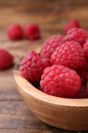 Photo of Tasty ripe raspberries in bowl on wooden table, closeup