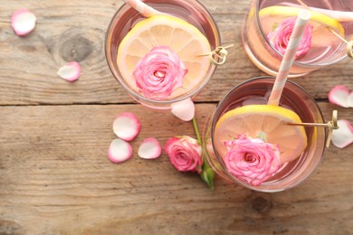 Refreshing drink with lemon and rose on wooden table, flat lay