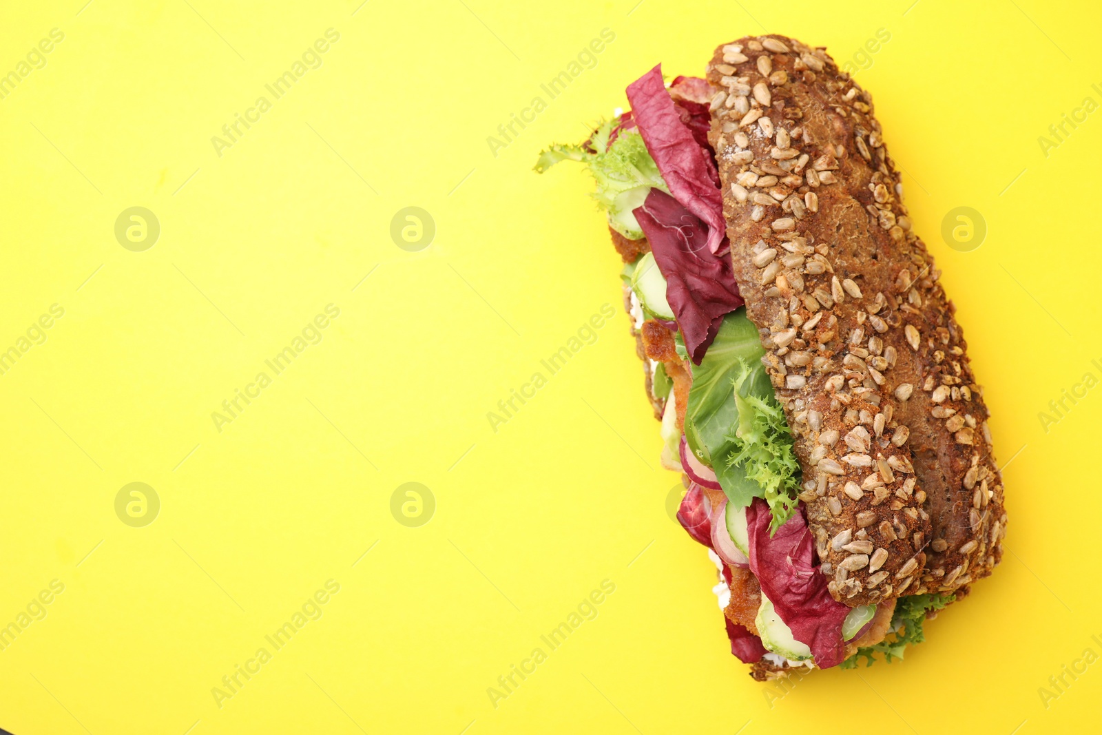 Photo of Delicious sandwich with schnitzel on yellow background, top view. Space for text
