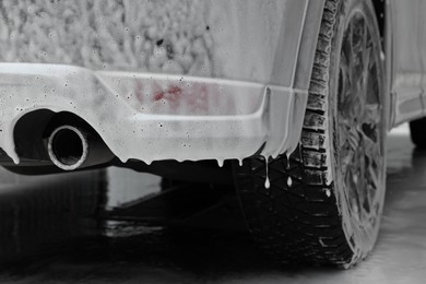 Auto with cleaning foam at car wash, closeup