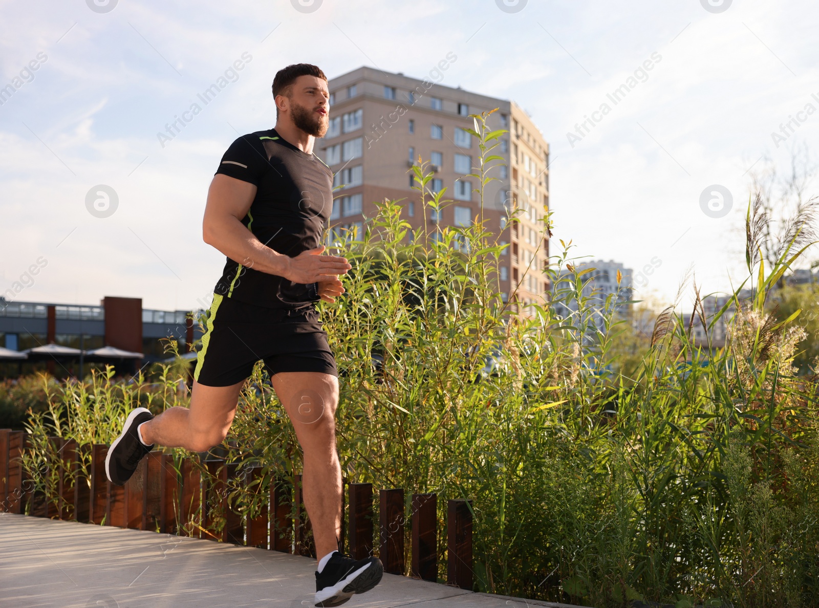 Photo of Young man running outdoors on sunny day. Space for text