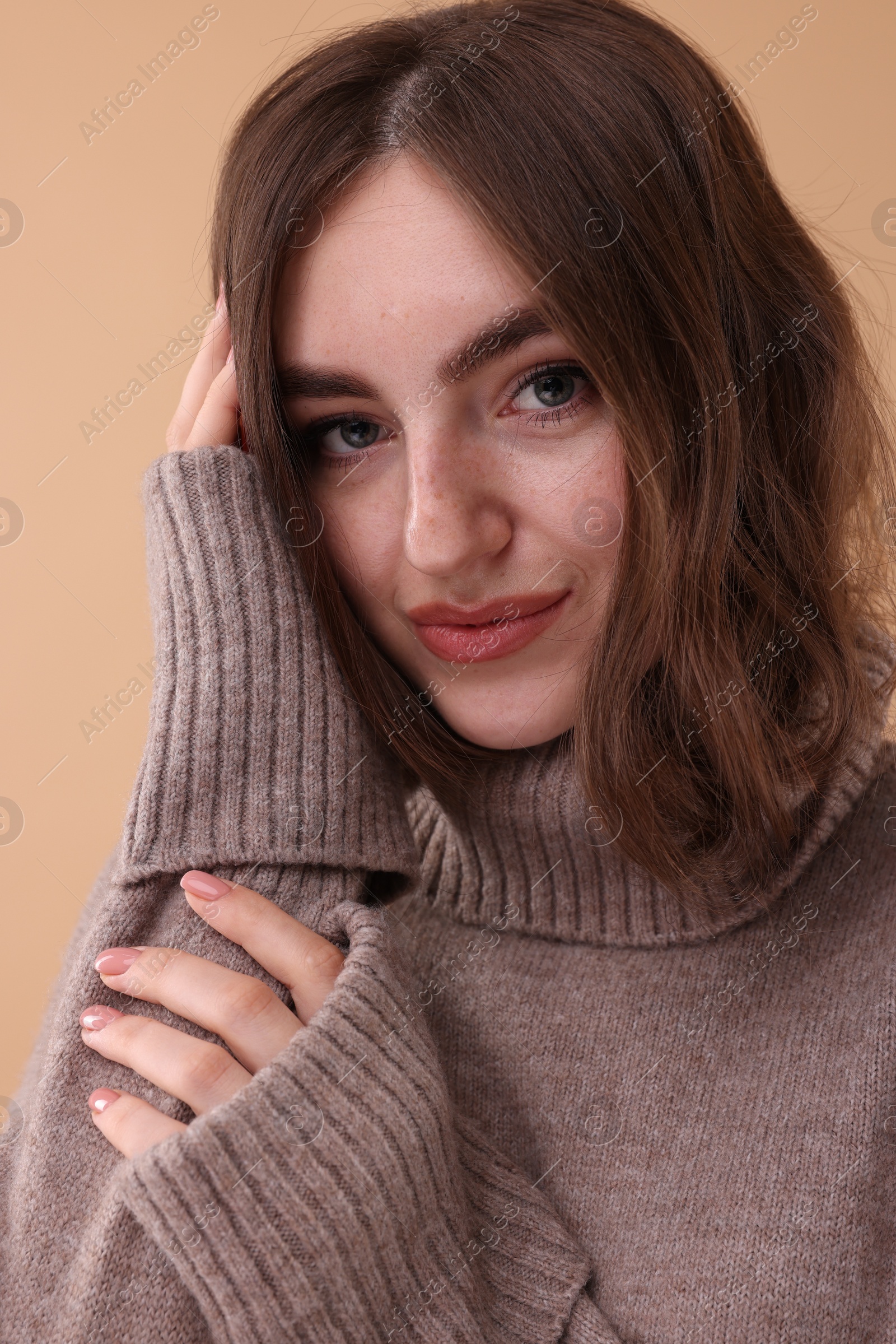 Photo of Portrait of beautiful young woman in warm sweater on brown background