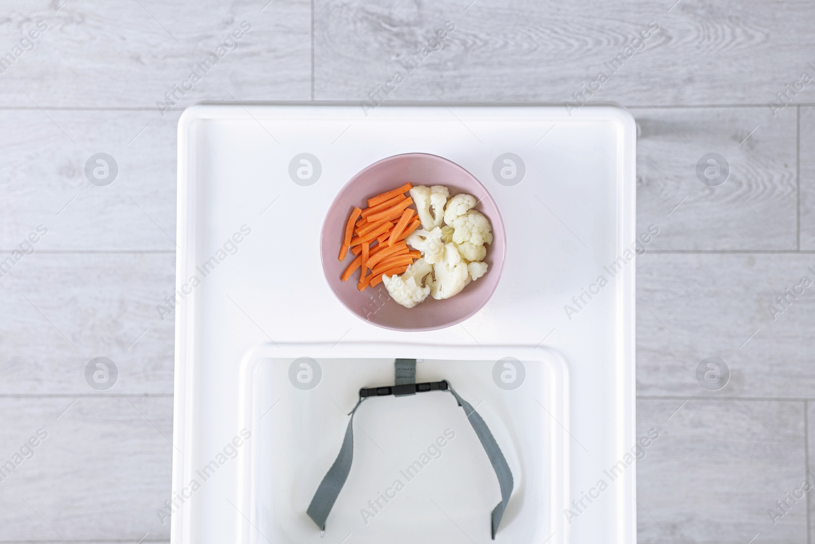 Photo of High chair with healthy baby food served on white tray indoors, top view