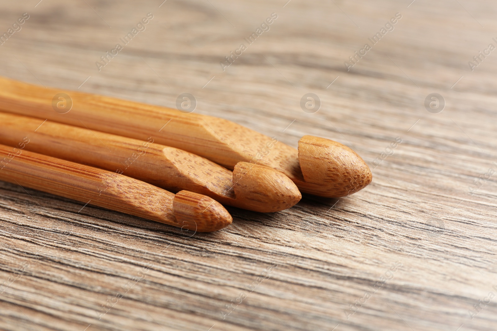 Photo of Three crochet hooks on wooden table, closeup