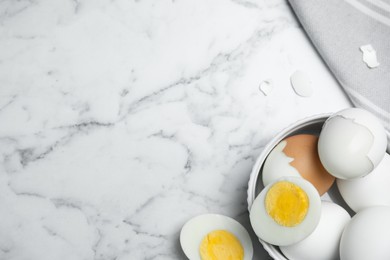 Hard boiled eggs and kitchen towel on white marble table, flat lay. Space for text