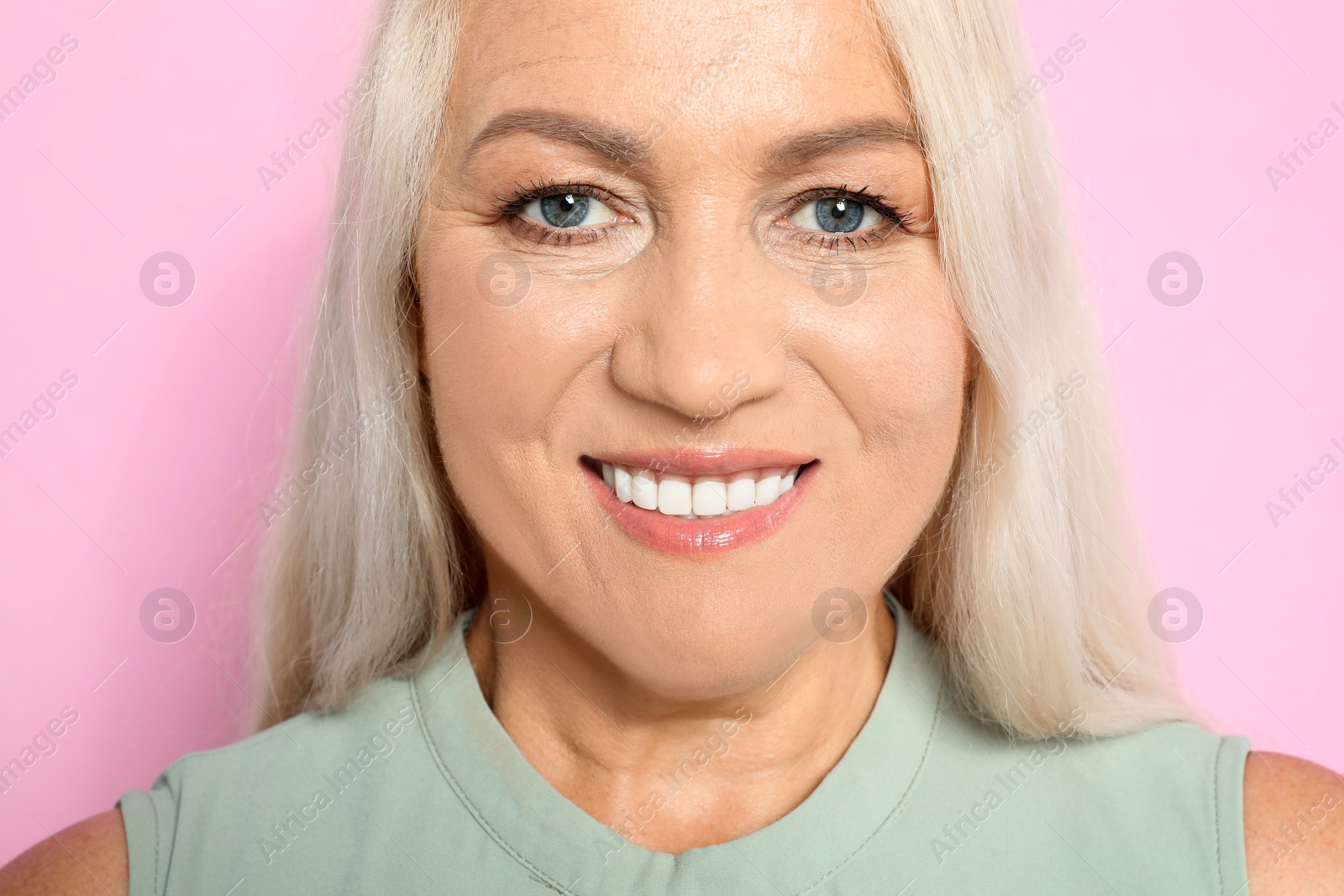 Photo of Portrait of mature woman with beautiful face on pink background