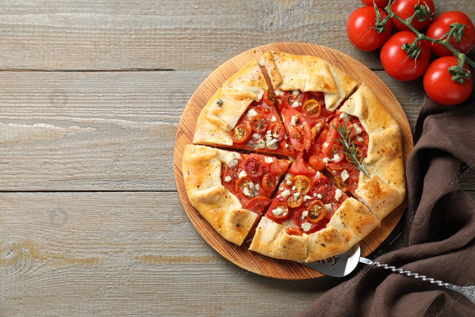 Photo of Tasty galette with tomato, rosemary and cheese (Caprese galette) on wooden table, top view. Space for text