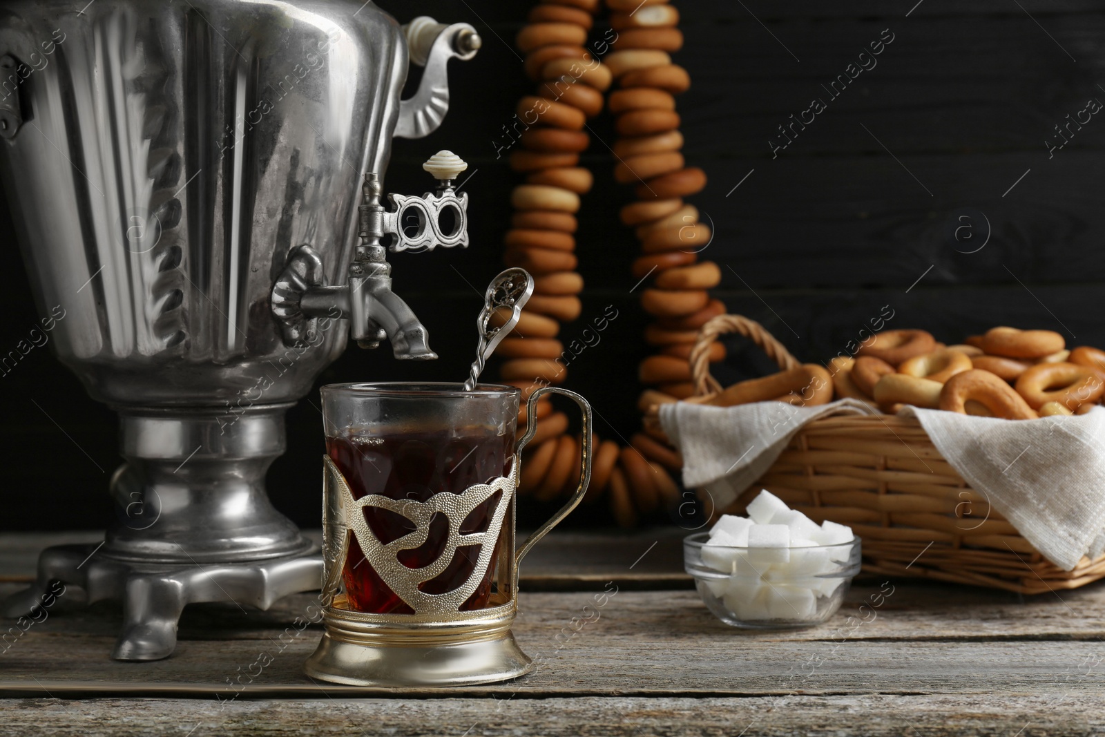 Photo of Delicious tea and ring shaped Sushki (dry bagels), focus on cup with samovar. Space for text