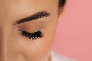 Beautiful young woman with long eyelashes on pink background, closeup. Space for text