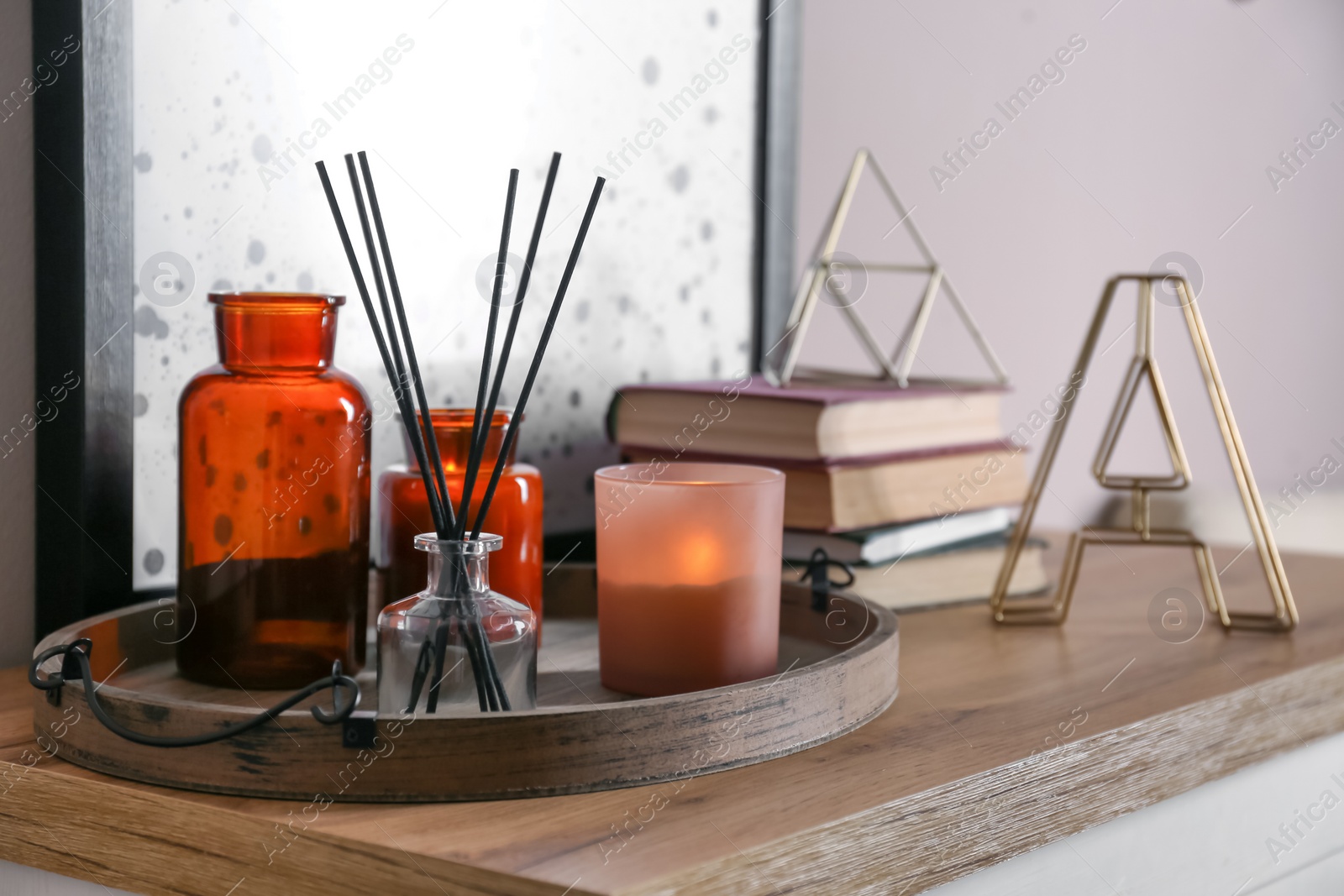 Photo of Wooden tray with air reed freshener and candles on table indoors