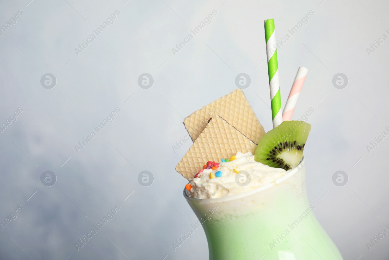 Photo of Glass with delicious milk shake on light background, closeup. Space for text