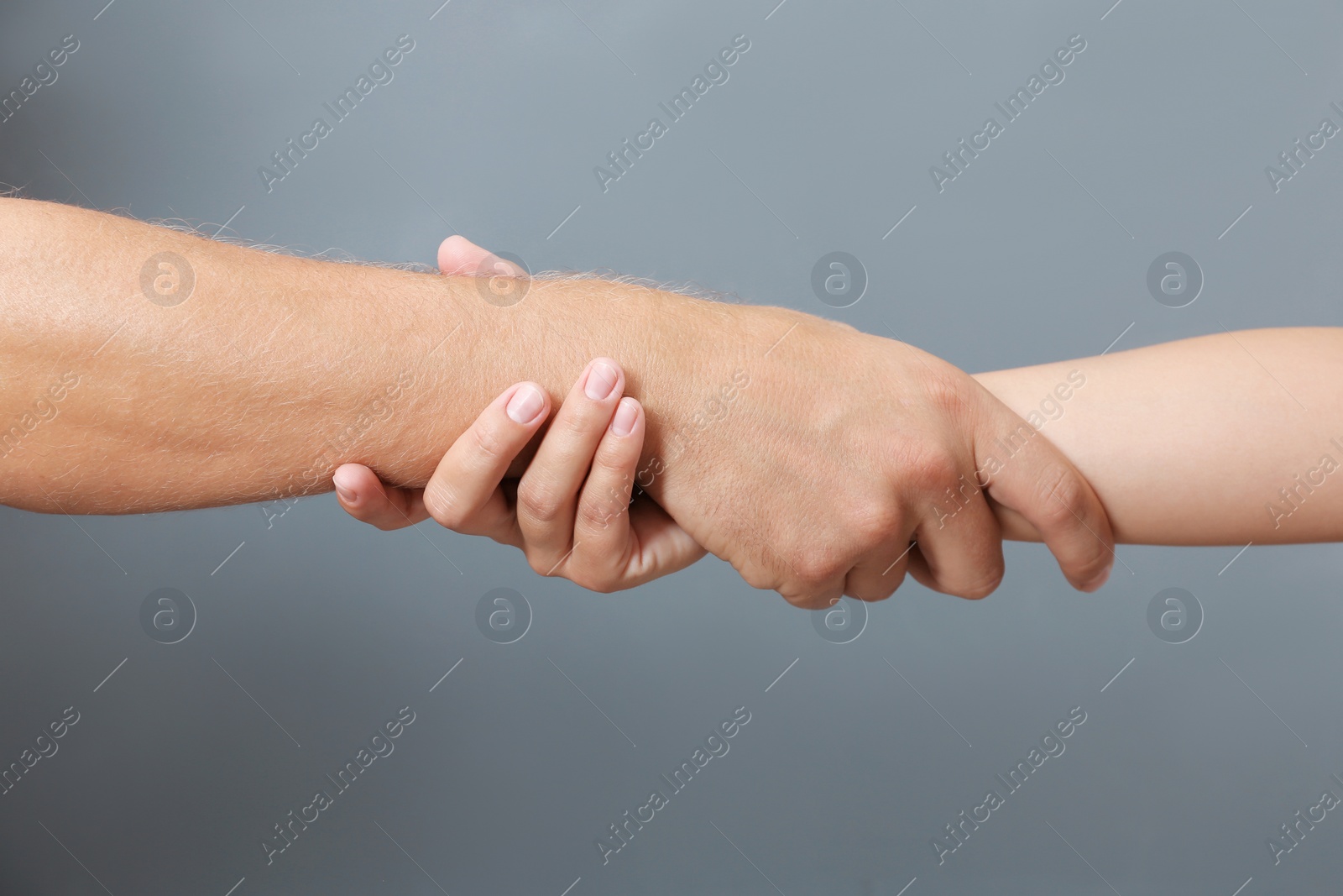 Photo of People holding hands together on gray background, closeup. Concept of support and help