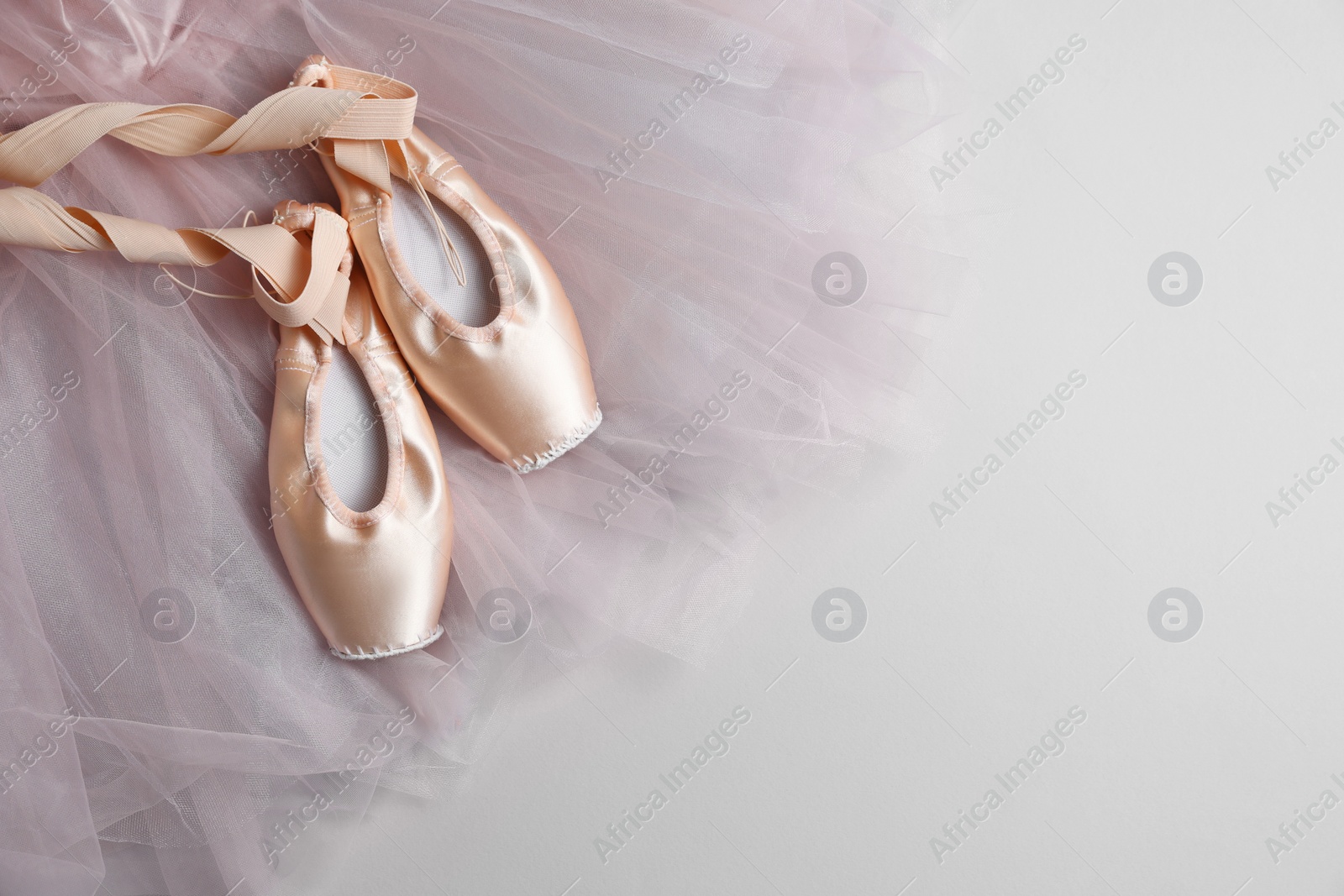 Photo of Ballet shoes. Elegant pointes and tutu on light grey background, top view. Space for text
