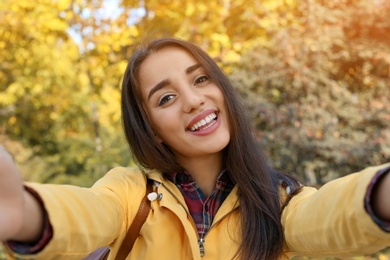 Photo of Young beautiful woman taking selfie in park. Autumn walk