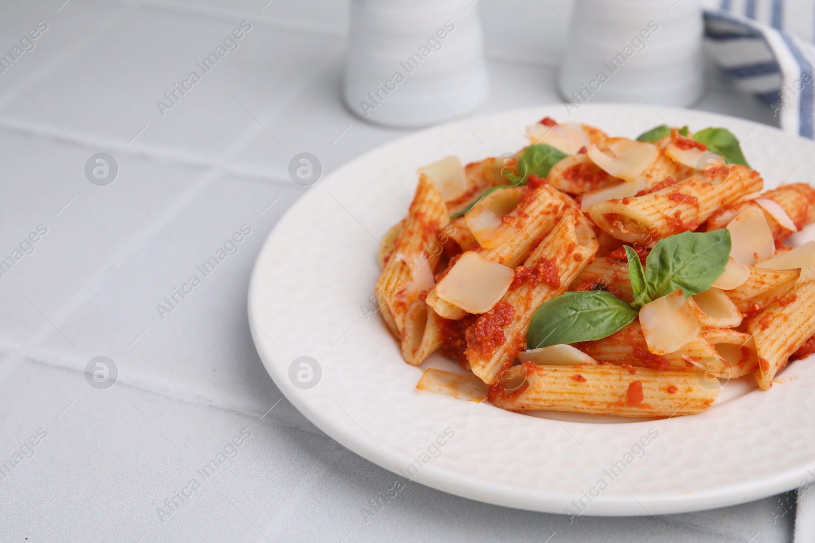 Photo of Tasty pasta with tomato sauce, cheese and basil on white tiled table