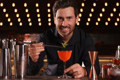 Photo of Bartender preparing fresh alcoholic cocktail in bar