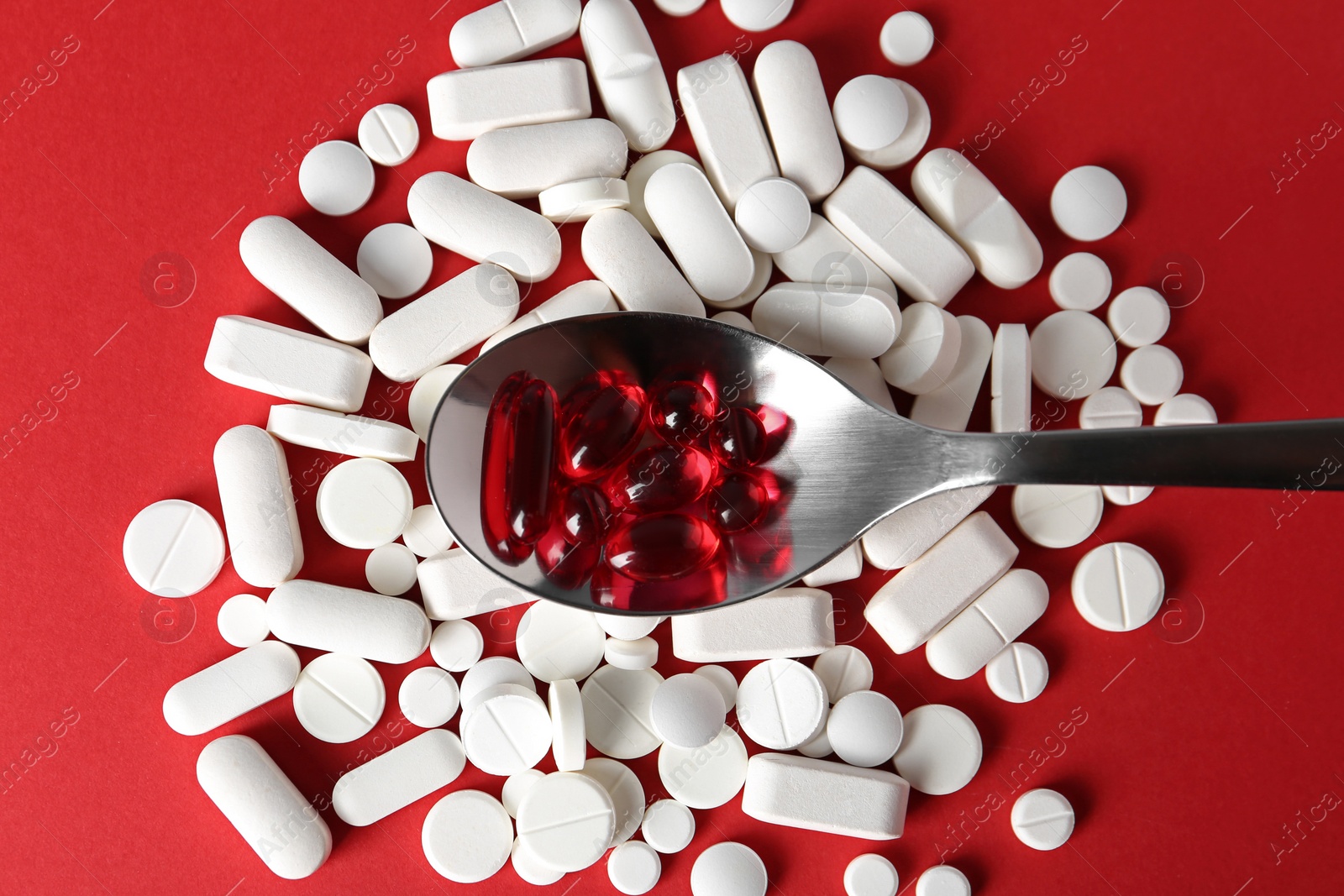 Photo of Spoon with weight loss pills on color background, top view