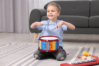 Little boy playing toy drum at home