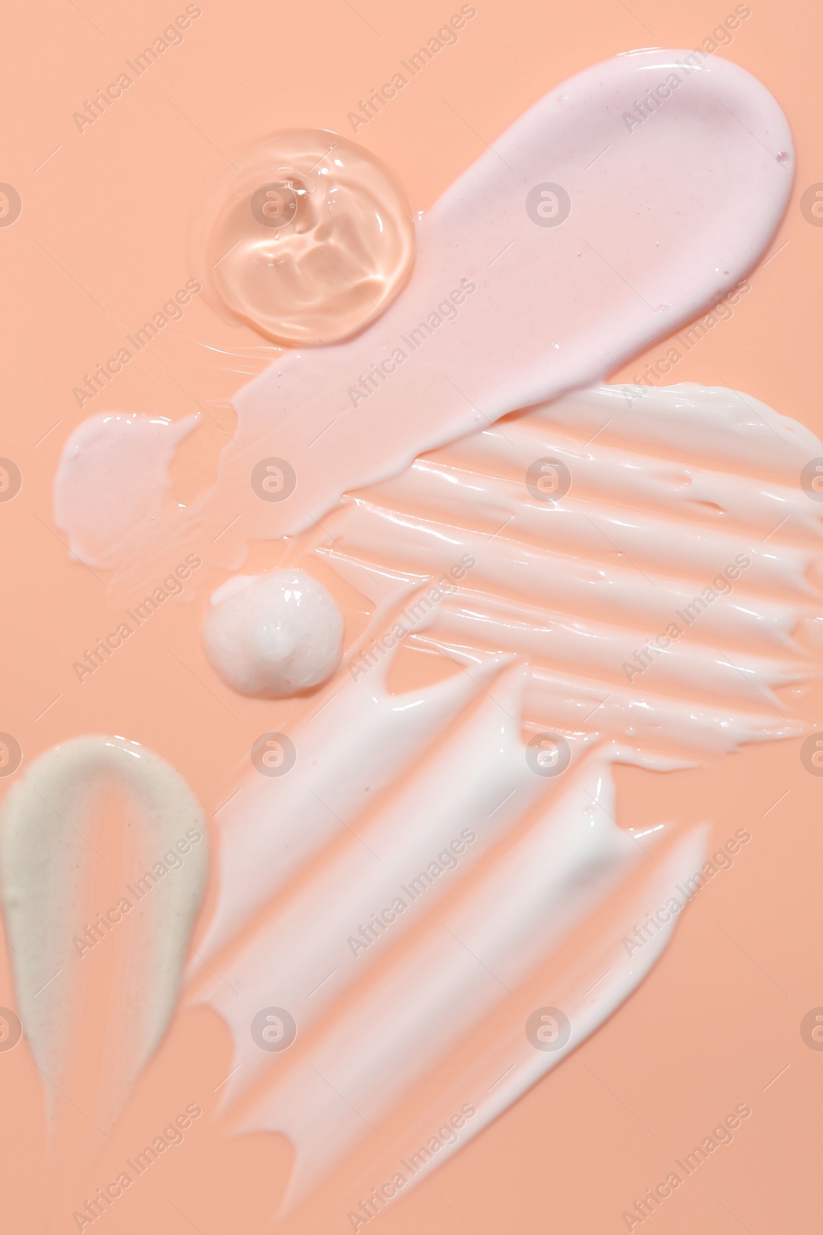 Photo of Samples of face cream on coral background, top view