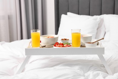 Photo of Tray with tasty breakfast on bed at home