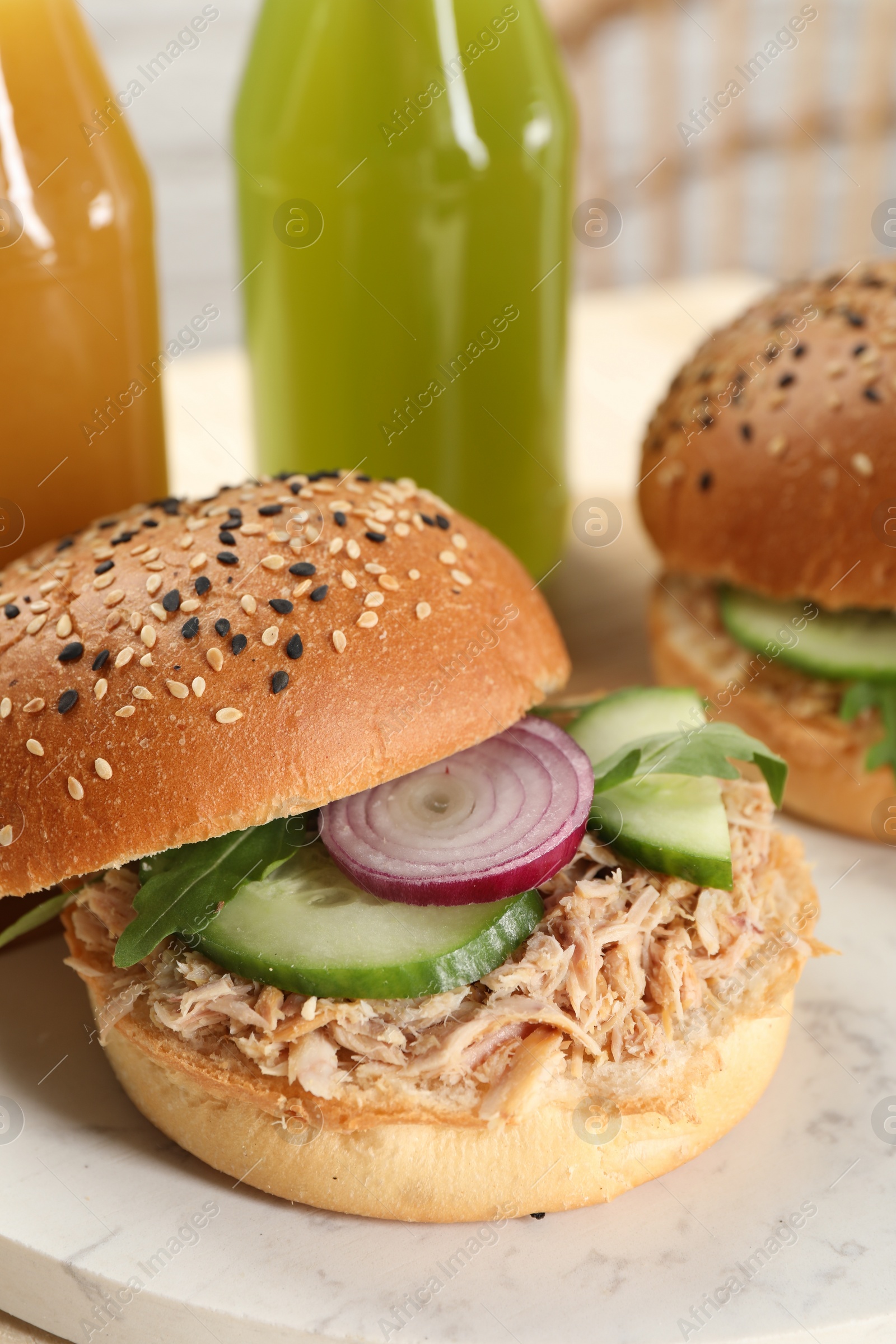 Photo of Delicious sandwiches with tuna, vegetables and bottles of juice on serving board, closeup