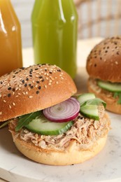 Photo of Delicious sandwiches with tuna, vegetables and bottles of juice on serving board, closeup