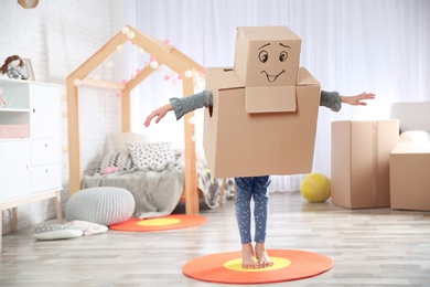 Photo of Cute little child wearing cardboard costume in bedroom