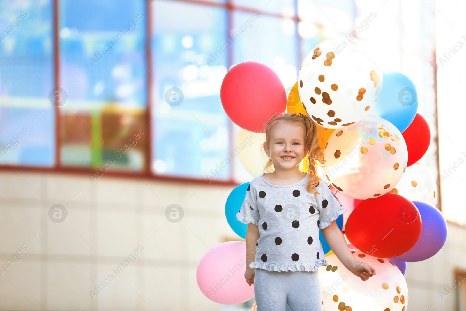 Photo of Little girl with colorful balloons outdoors on sunny day