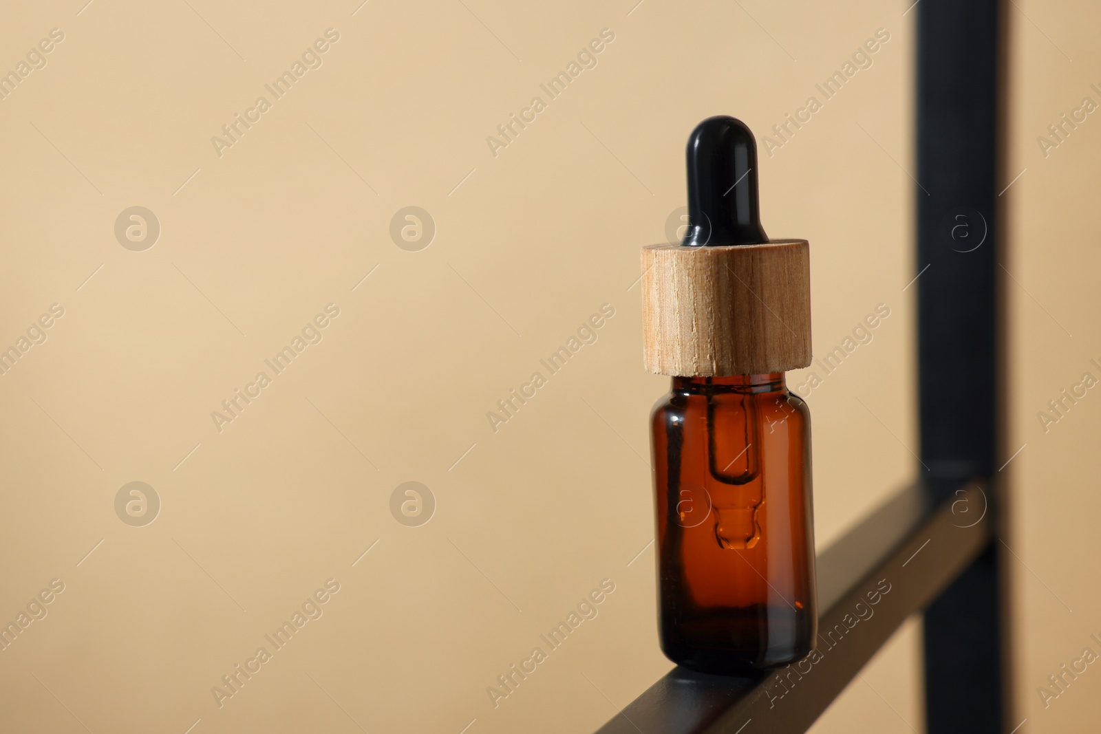 Photo of Glass bottle of essential oil on dark beige background, closeup. Space for text