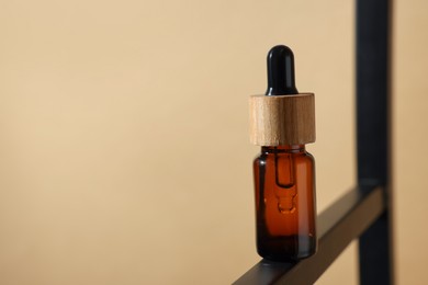 Glass bottle of essential oil on dark beige background, closeup. Space for text