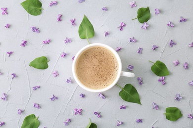 Flat lay composition with beautiful blossoming lilac and cup of coffee on light background. Spring flowers