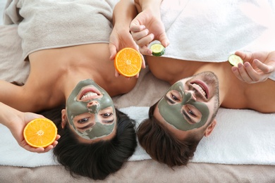 Photo of Happy couple enjoying facial treatment procedure in spa salon, above view